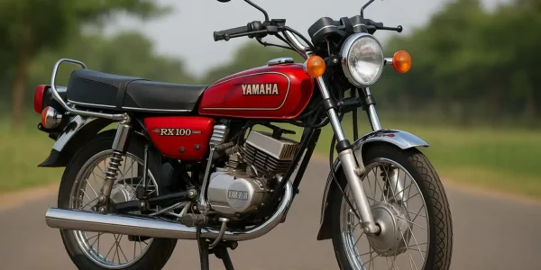 Yamaha RX 100 red vintage motorcycle with chrome exhaust and round headlamp parked on a road with trees in the background